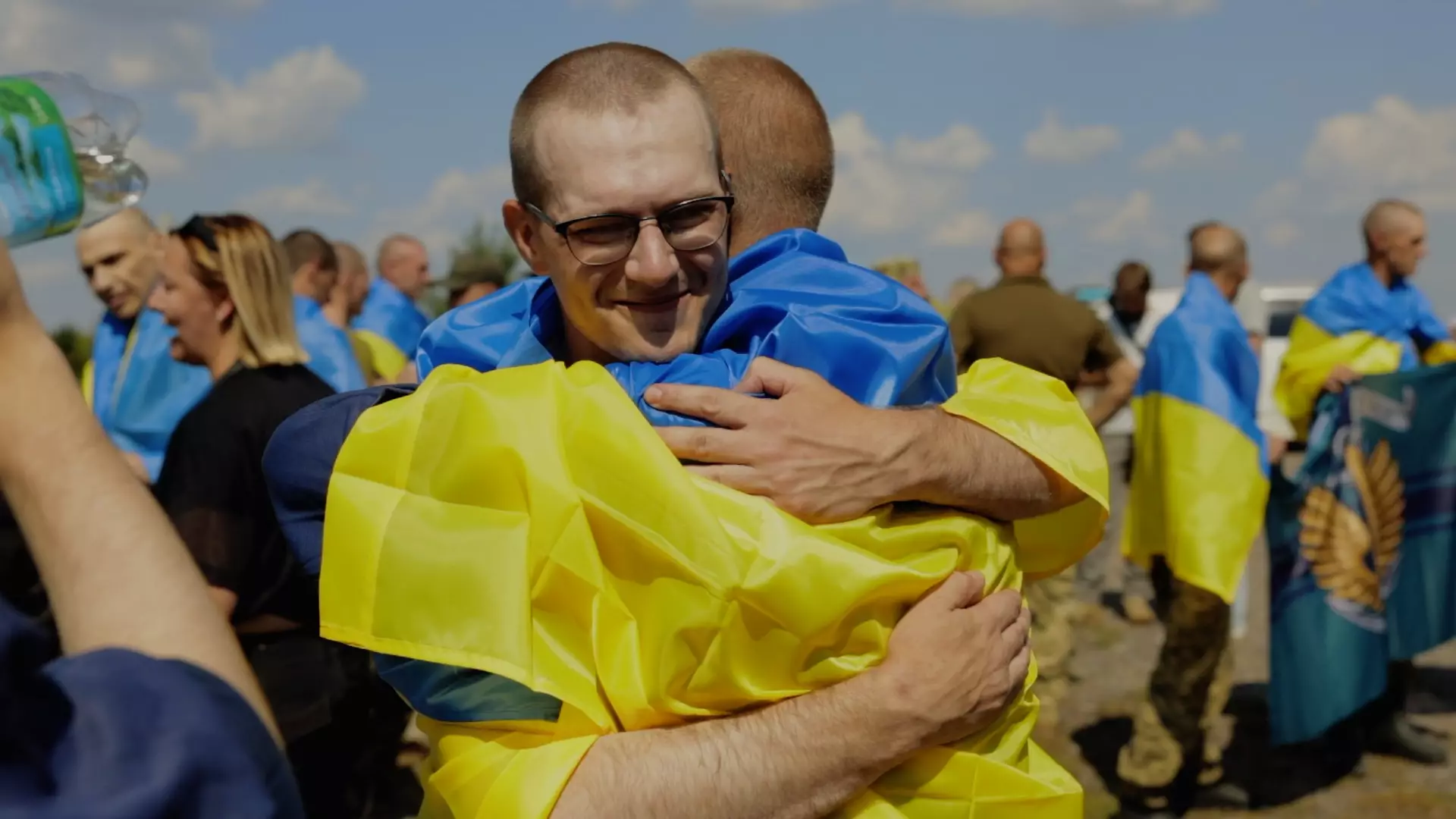 Звільнений з полону український захисник усміхається в обіймах побратимів під час зустрічі